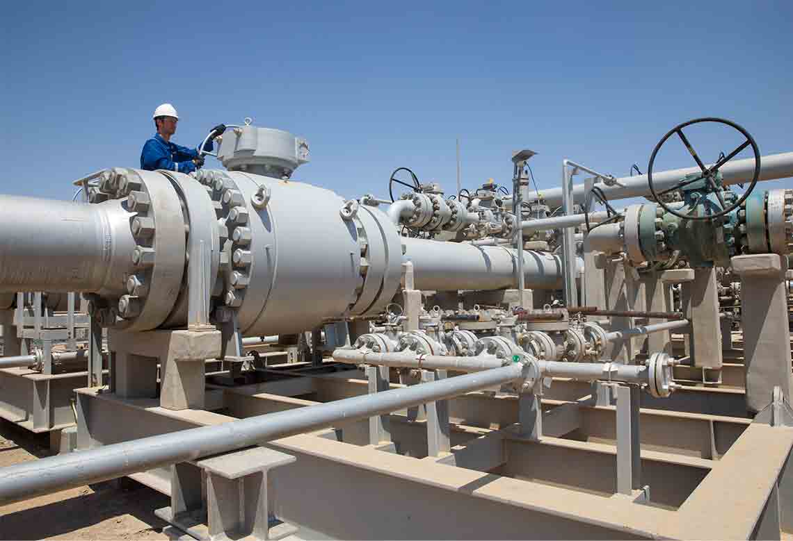 Photo of a worker in blue coveralls working at a gas processing facility